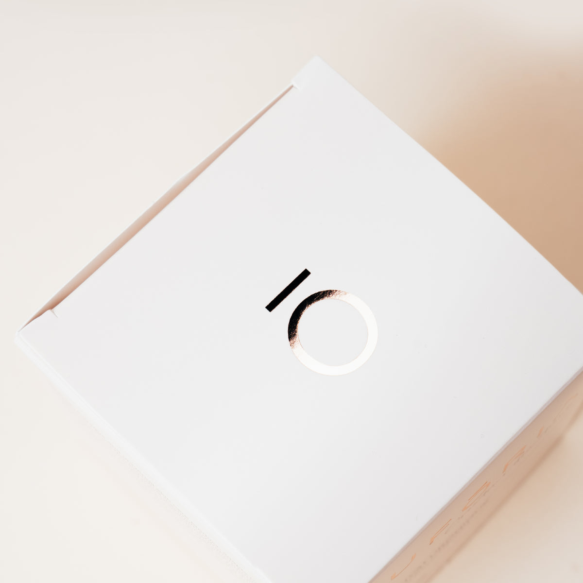 Boîte rose nacré Euforia vue de dessus avec le logo circulaire rose gold, sur fond clair.